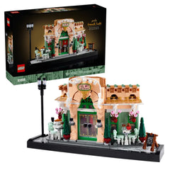 LEGO® Icons French Café construction set featuring a charming pink façade with green double doors, surrounded by decorative planters and outdoor seating. A classic streetlight stands beside the café, enhancing its inviting atmosphere.