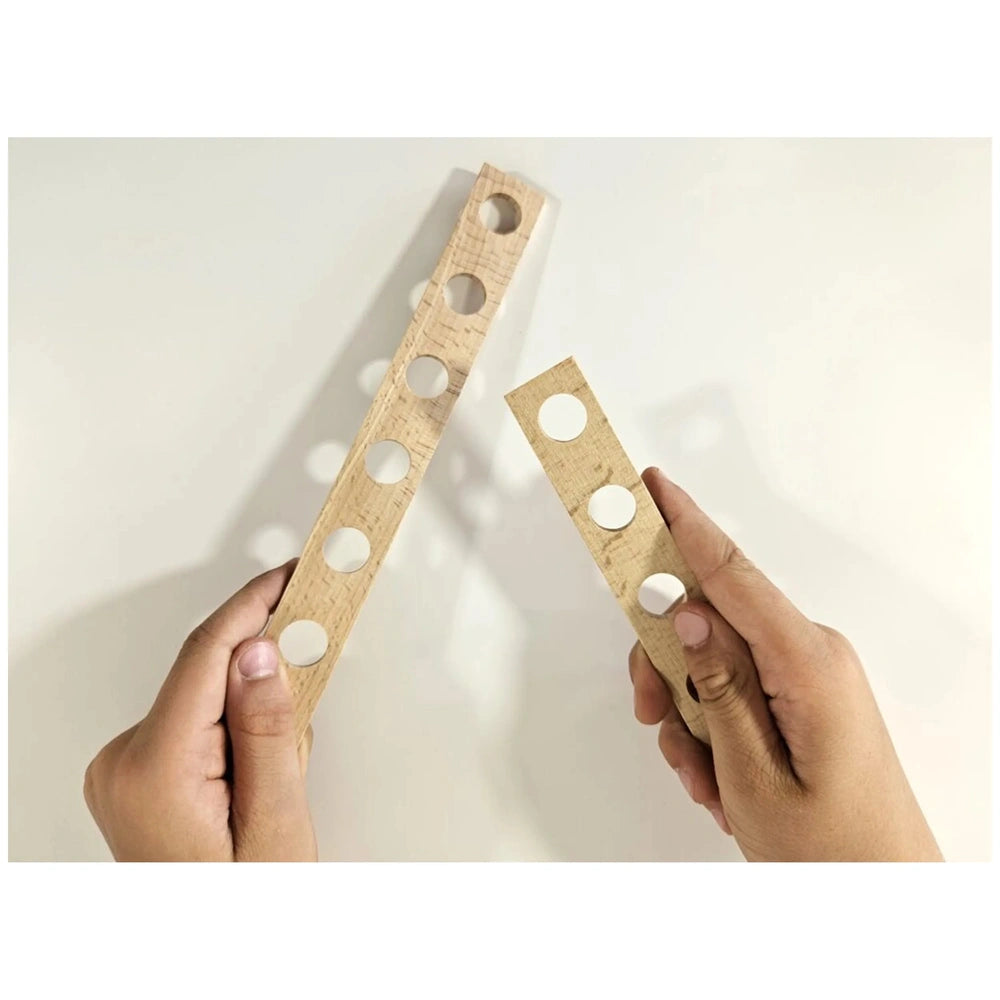 Child's hands holding wooden planks with holes from Alexander Maly Constructor Junior set.