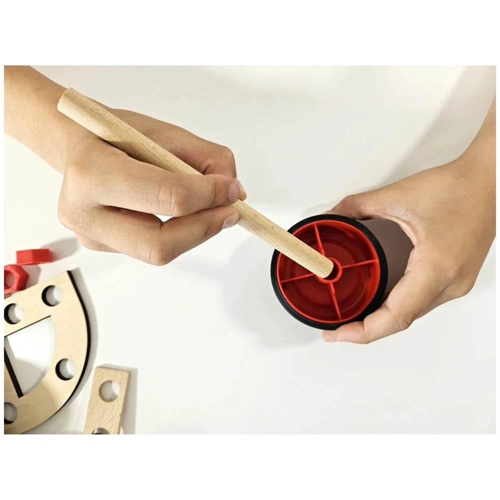 Hands assemble Alexander Maly Constructor Junior set, using a wooden stick and red plastic connector pieces.