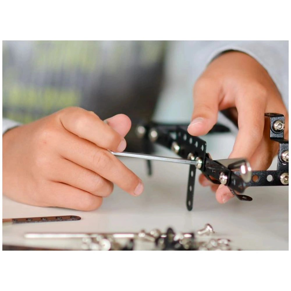 Child assembling Alexander Maly Constructor Pro Manta set using metal plates and screws, focusing on engineering skills.
