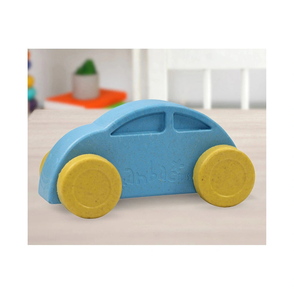 Blue toy car with yellow wheels on a table in a bright playroom setting.