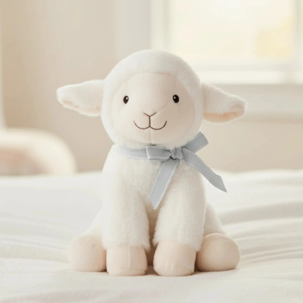 Artesavi - White Lamb Plush 18 Cm, a soft toy with a white body and gray face, sitting on a white surface with a bow.