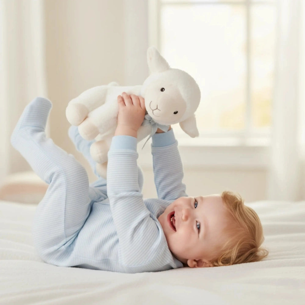 Artesavi White Lamb Plush: A joyful child cuddles a white lamb plush on a soft bed, basking in warm, natural light.
