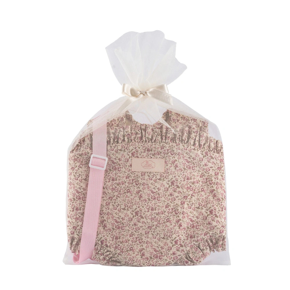 Floral-patterned baby carrier with pink strap in a tulle bag, tied with a beige bow, from Asi Dolls Martina Collection.