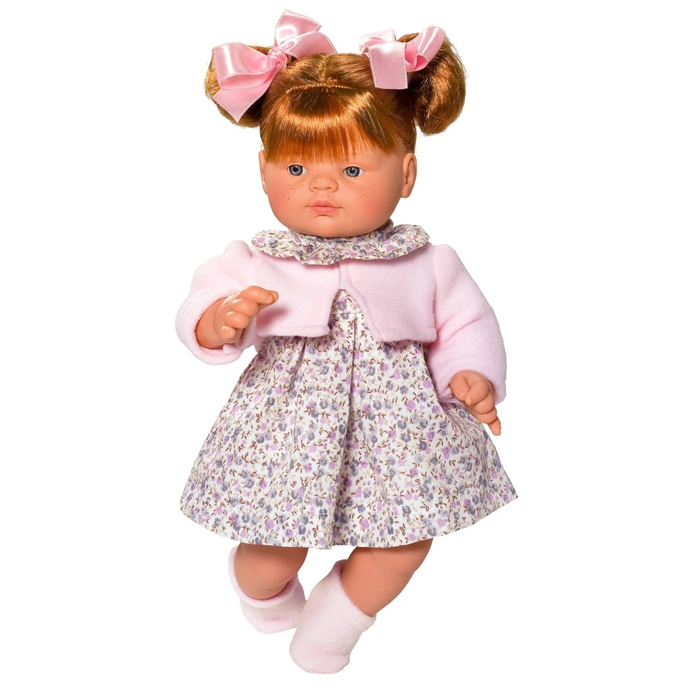 Red-haired doll with pigtails in pink jacket and gray floral dress, wearing pink bows and socks.