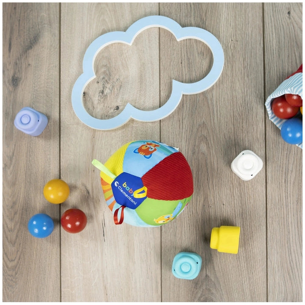 Baby Clementoni Animal Friends Musical Ball is surrounded by colorful toys on a wooden surface, creating a playful scene.