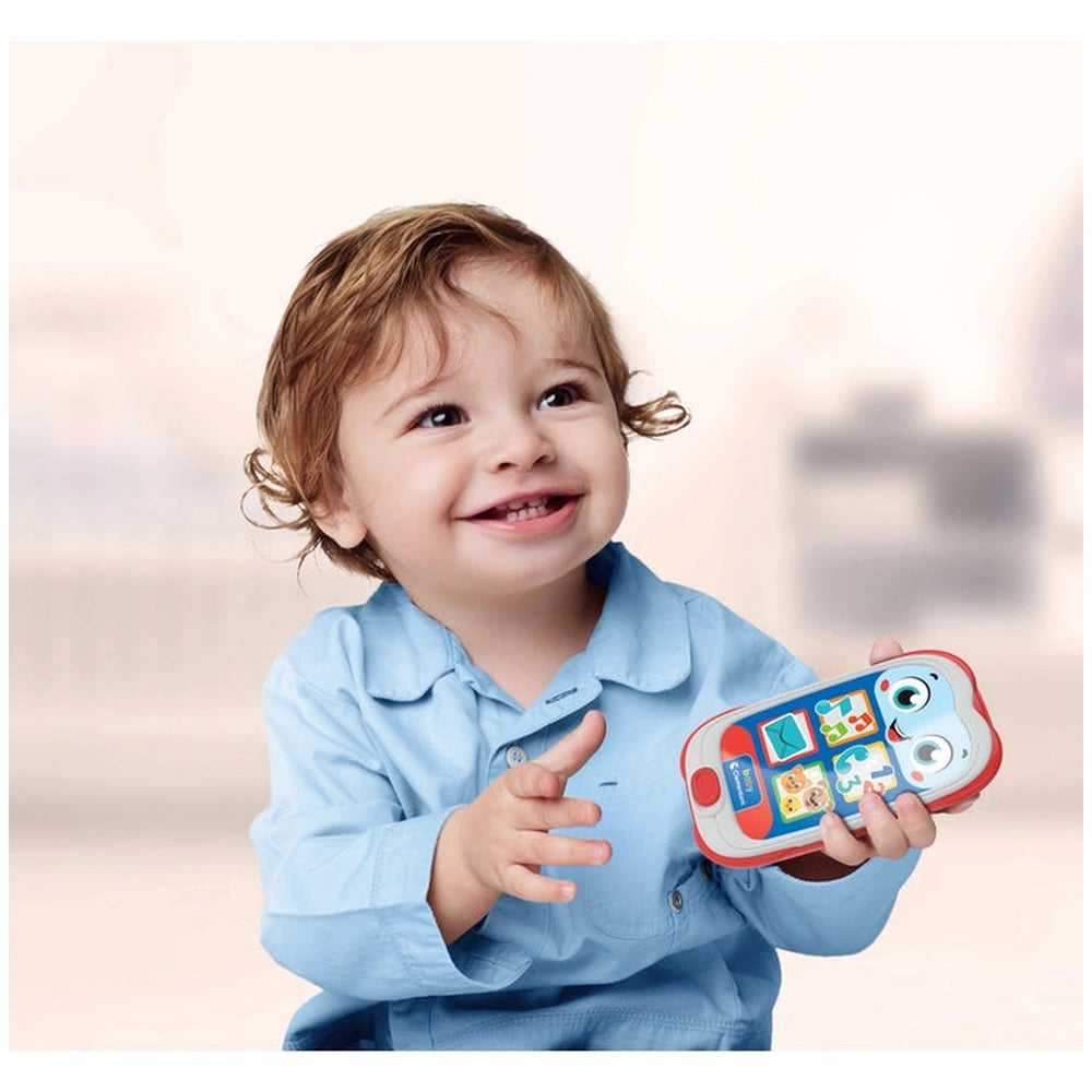 Baby Clementoni smartphone toy in a child's right hand, with a smiling young child in a blue shirt and curly hair.