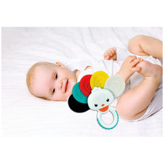 Baby Clementoni Rainbow Peacock Rattle rests on a smiling child's chest, with a blue ring around its neck against a white she