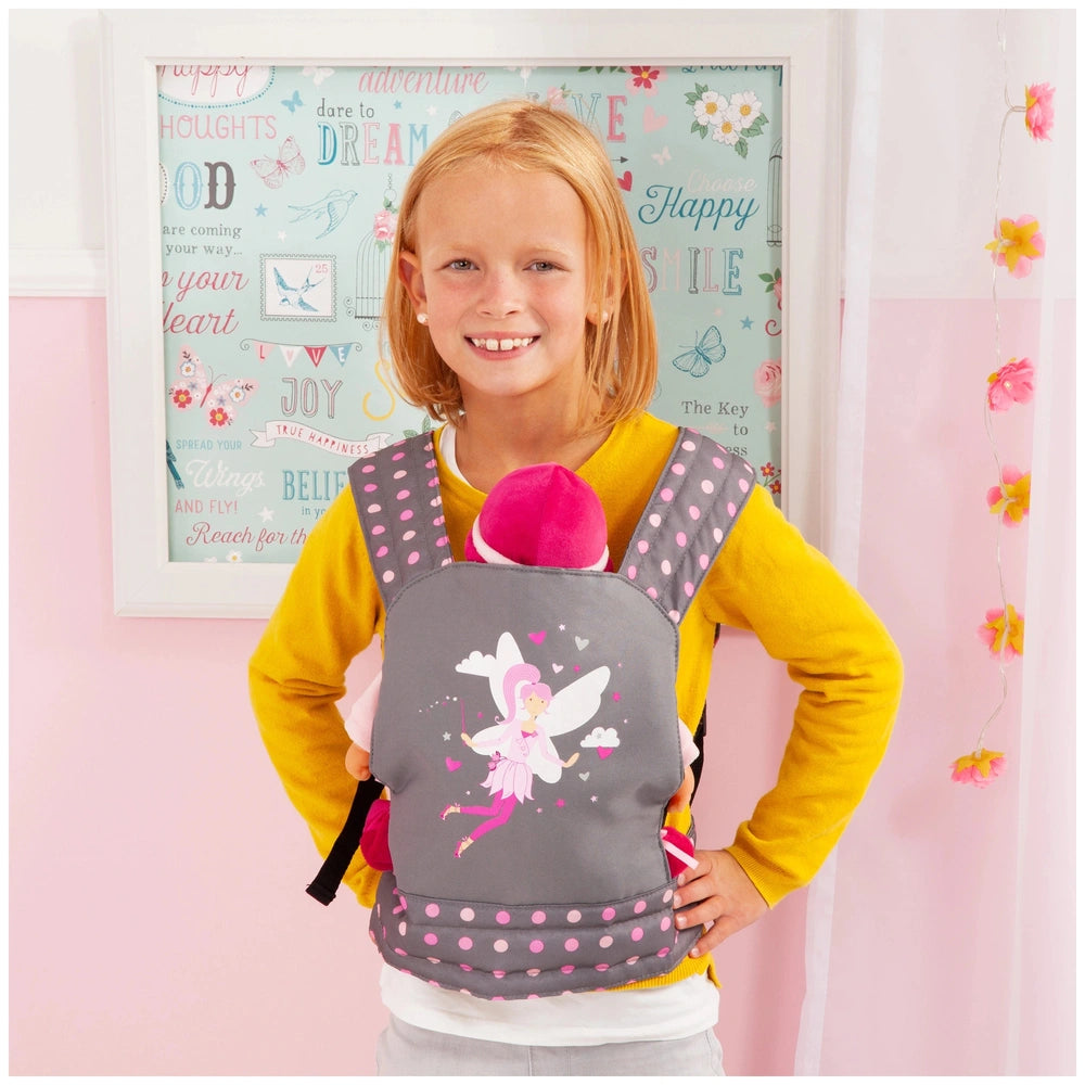 BAYER DESIGN Doll Carrier in gray and pink, held by a smiling girl in a yellow sweater against a colorful poster backdrop.