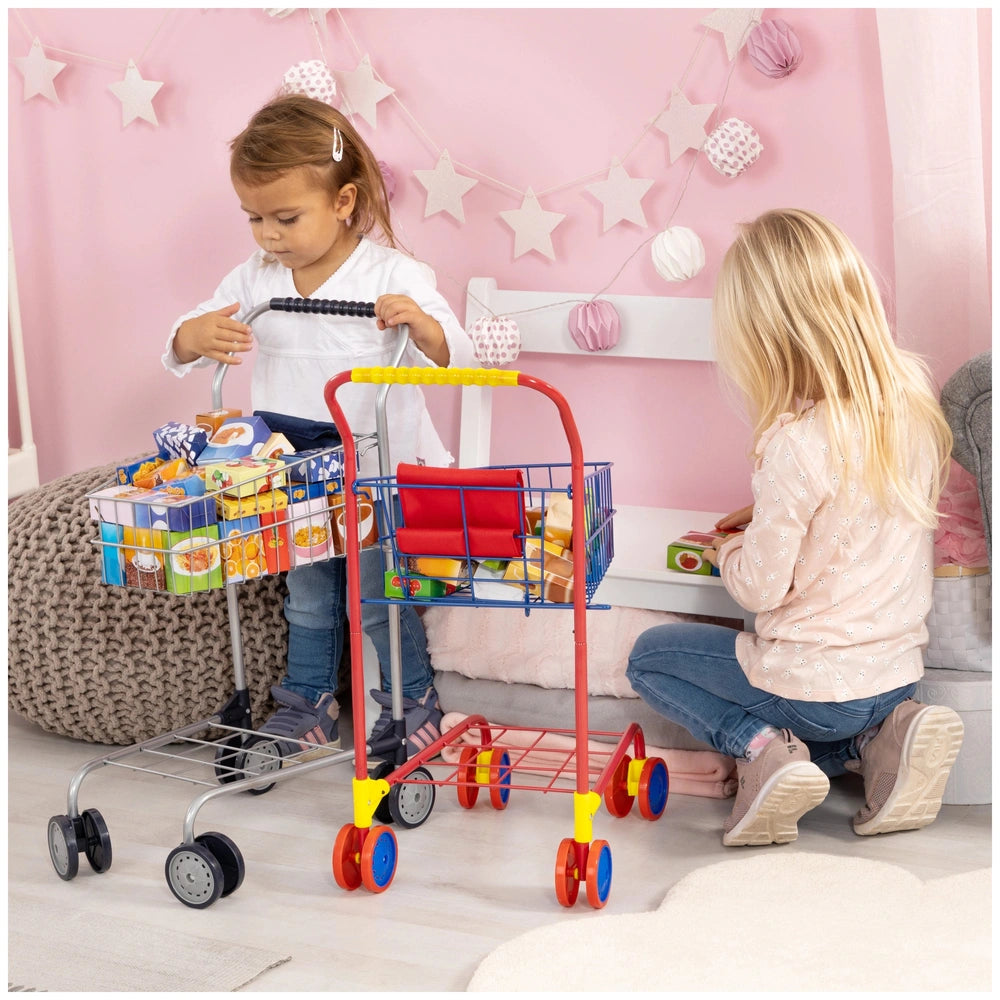 BAYER DESIGN shopping cart with colorful food packages, pushed by two girls in a pink room with light wood floor.