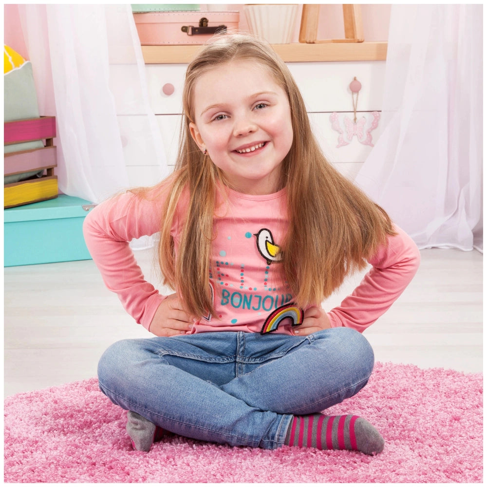 BAYER DESIGN Twin Pram in Unicorn Blue Pink, with a young girl on a pink shag rug, surrounded by a light pink wall and colorf