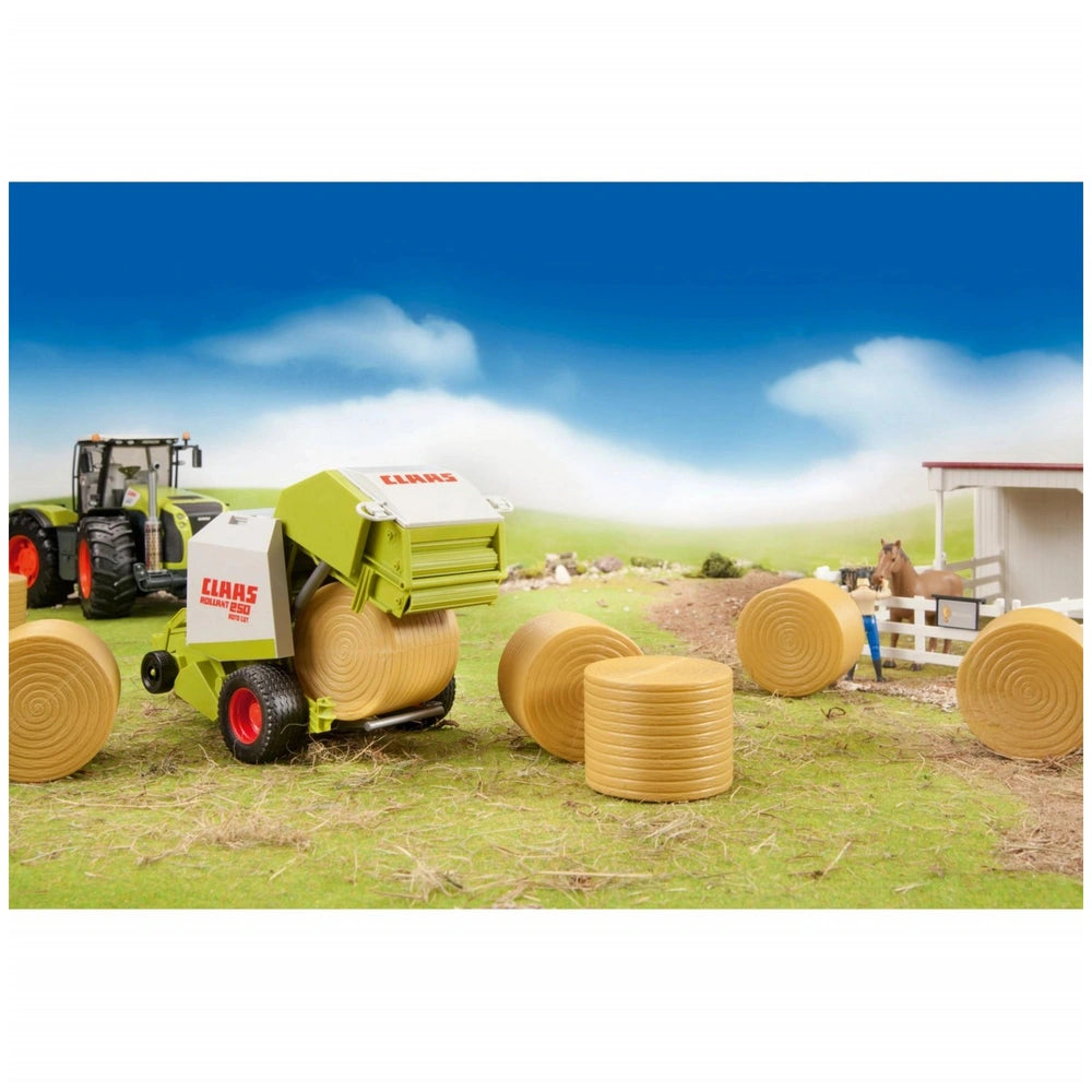 Toy Claas Rollant 250 baler with ochre hay bales on a farm playset, blue sky background.