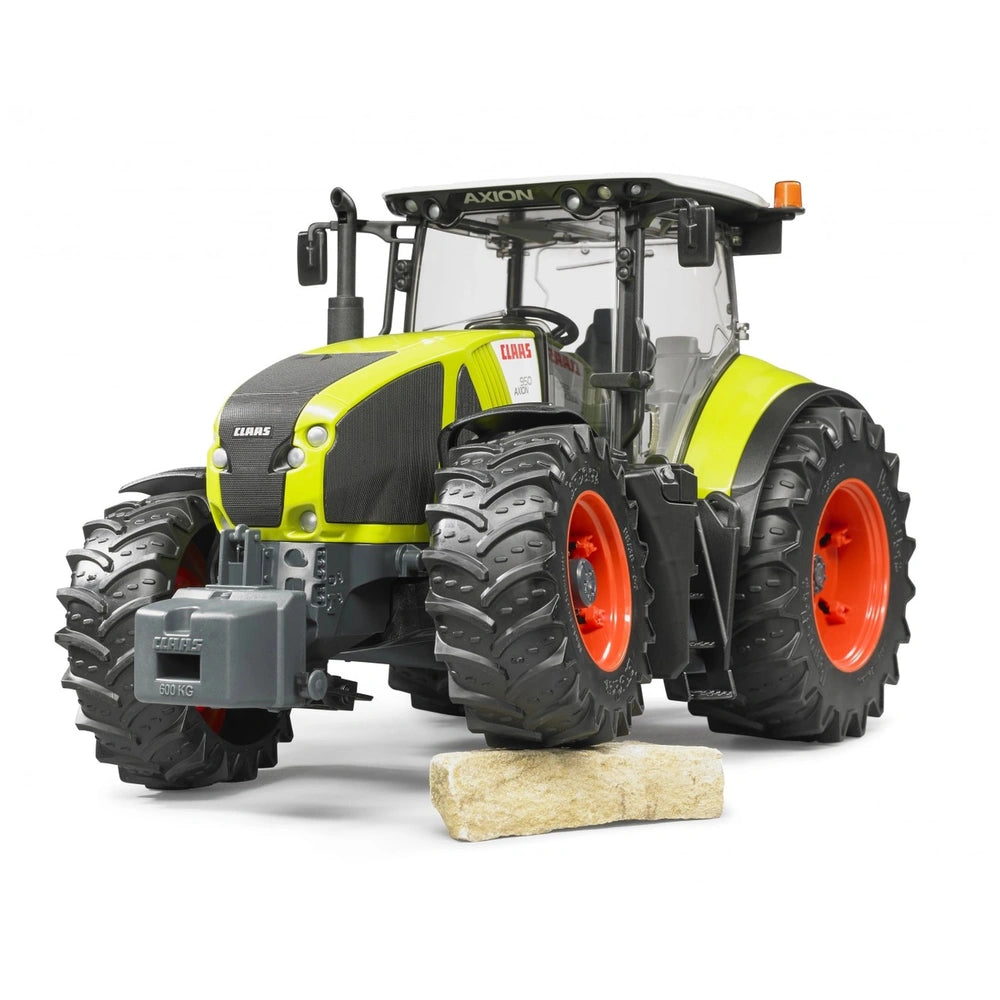 Bruder Claas Axion 950 toy tractor, lime green and black, with red wheels, on a rock, viewed from front-left angle.