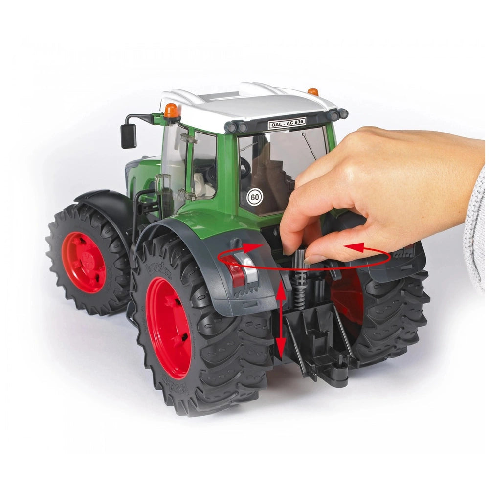 Hand adjusting steering on a green BRUDER Fendt 936 Vario toy tractor, showcasing large red wheels and detailed cabin.