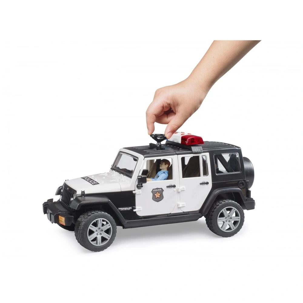 Toy Jeep Wrangler Police vehicle with policeman figure, hand steering. Black and white design with red siren on top.