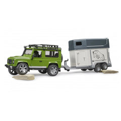 Green Land Rover Defender toy with detailed horse trailer on rocky terrain.