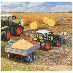 Toy tractor and trailer in a wheat field with hay bales and a worker, showcasing BRUDER's realistic agricultural play set.