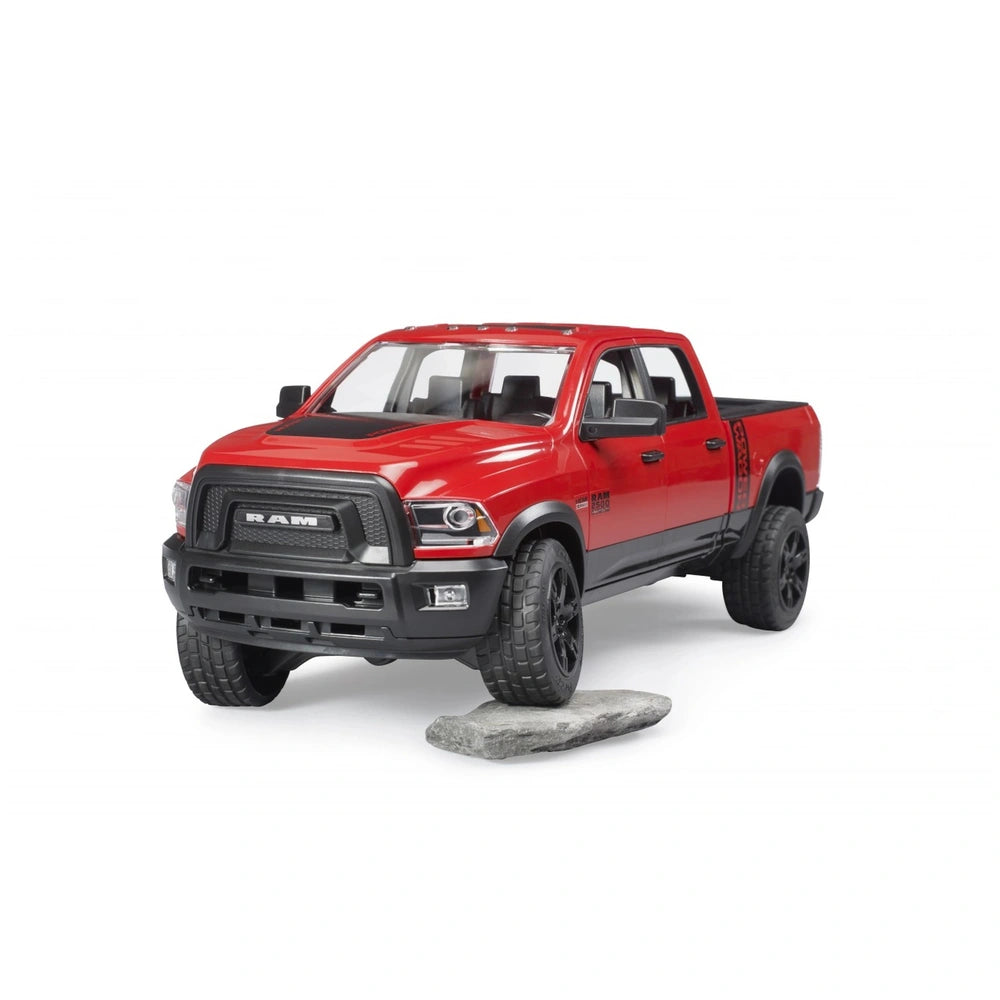 Red Bruder RAM 2500 Power Wagon toy on a rock, featuring black wheels and detailed grille, angled from the front left.
