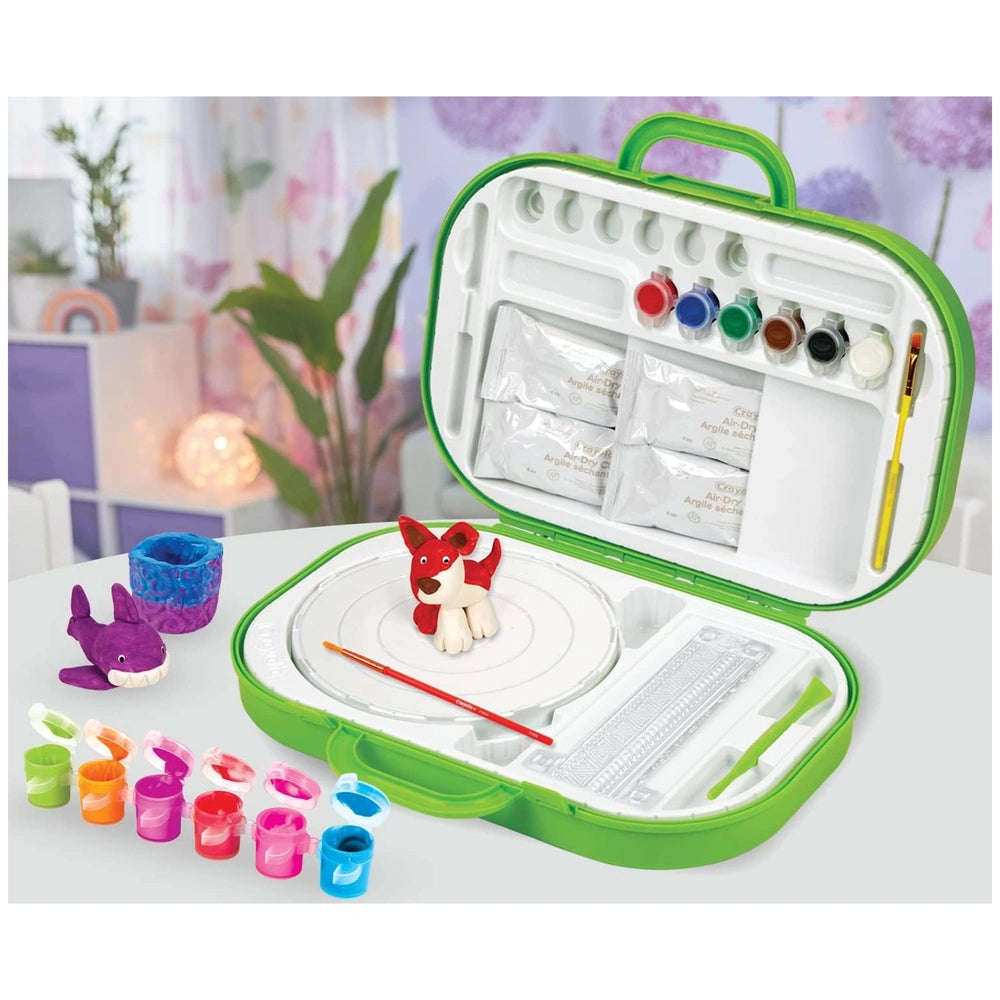 Crayola Clay Sculpting Station features a red and white toy in a green case with "100 Pieces" and arts symbols on a white sur