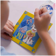 Diamond Dotz Dotzies features Paw Patrol Marshall, a white cat in red and yellow outfit on blue paper with yellow border.