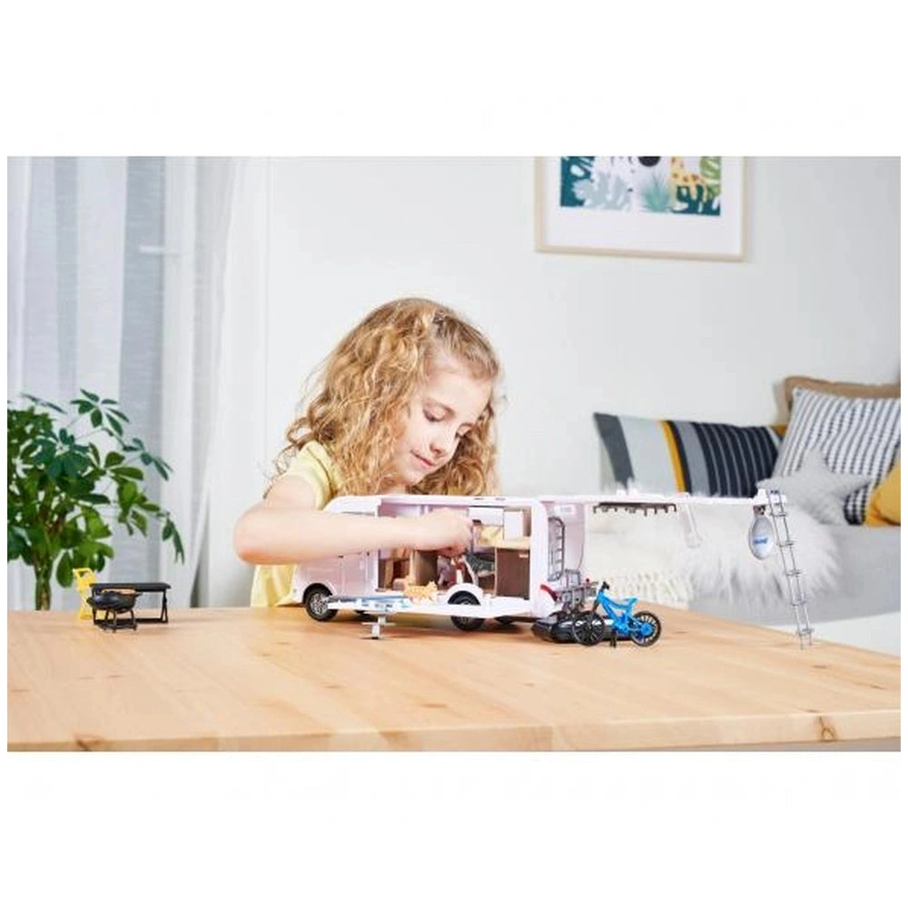 Blonde girl playing with a white toy car on a wooden table in a lifestyle scene with a striped couch and green plant.
