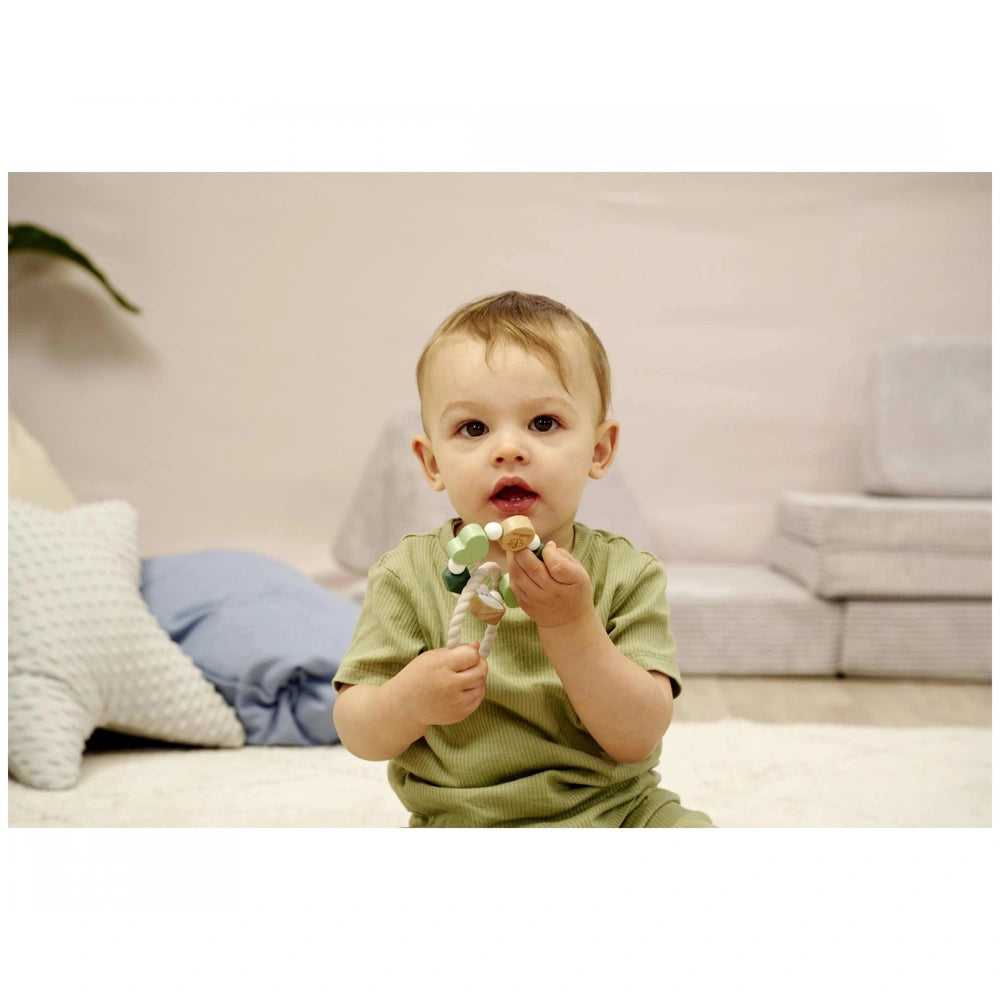 Eichhorn Baby HiPP Grapper is held by a young child in a soft pastel indoor setting with light-colored carpet and furniture.