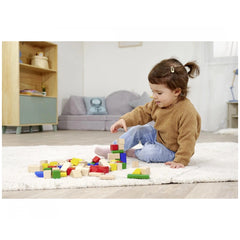 Eichhorn baby wooden colored blocks scattered around a focused child playing on a light rug in a cozy, neutral-toned room.