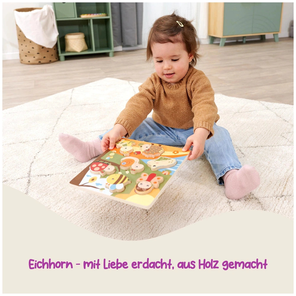 Eichhorn Bee-Happy Sensory Puzzle is featured with a child reading a colorful book on a patterned white rug indoors.