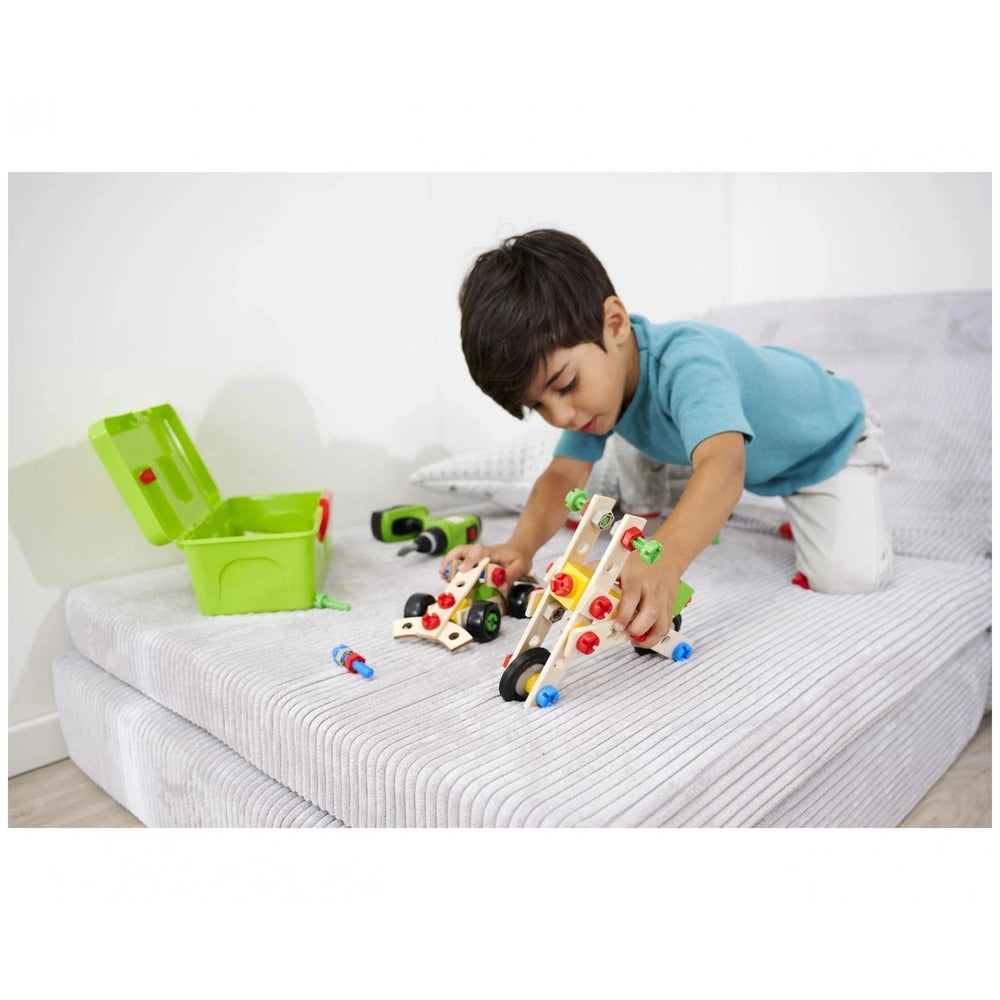 Eichhorn Constructor 3in1 Race Car set in use by a young boy on a bed, featuring colorful components and a train track.