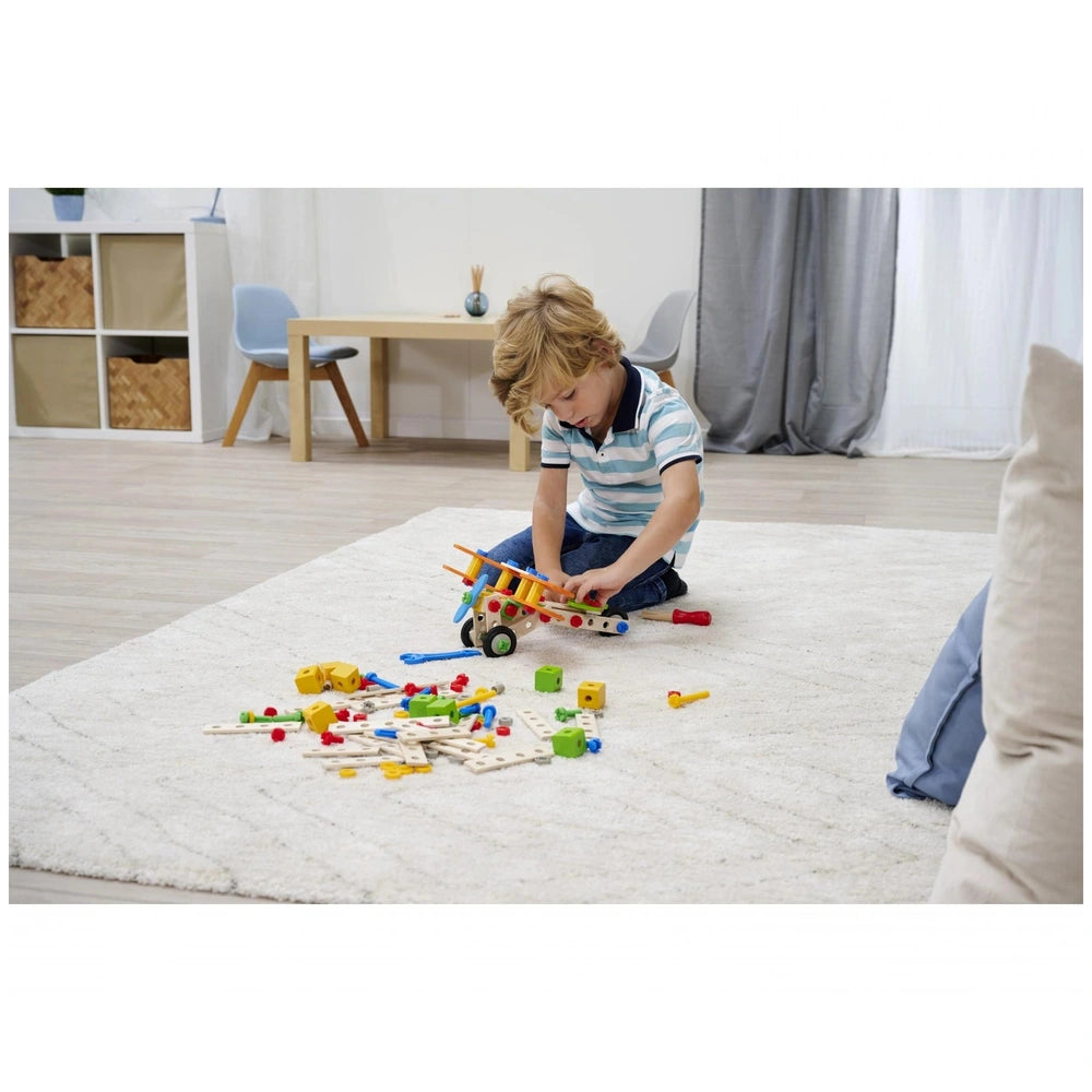 Eichhorn Constructor 4 in 1 construction set is scattered around a young child playing on a white shag rug.