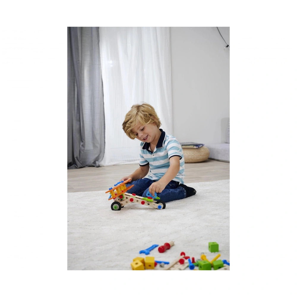 Eichhorn Constructor 4 in 1 construction set toys are scattered on a white carpet as a child plays with a colorful vehicle.
