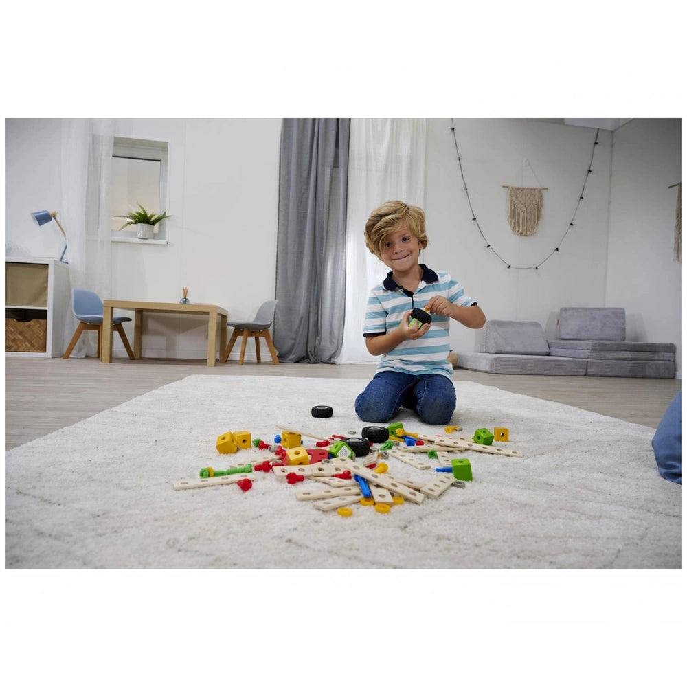 Eichhorn Constructor Accessories construction set toys are spread on a shaggy carpet, with a smiling child engaged in play.