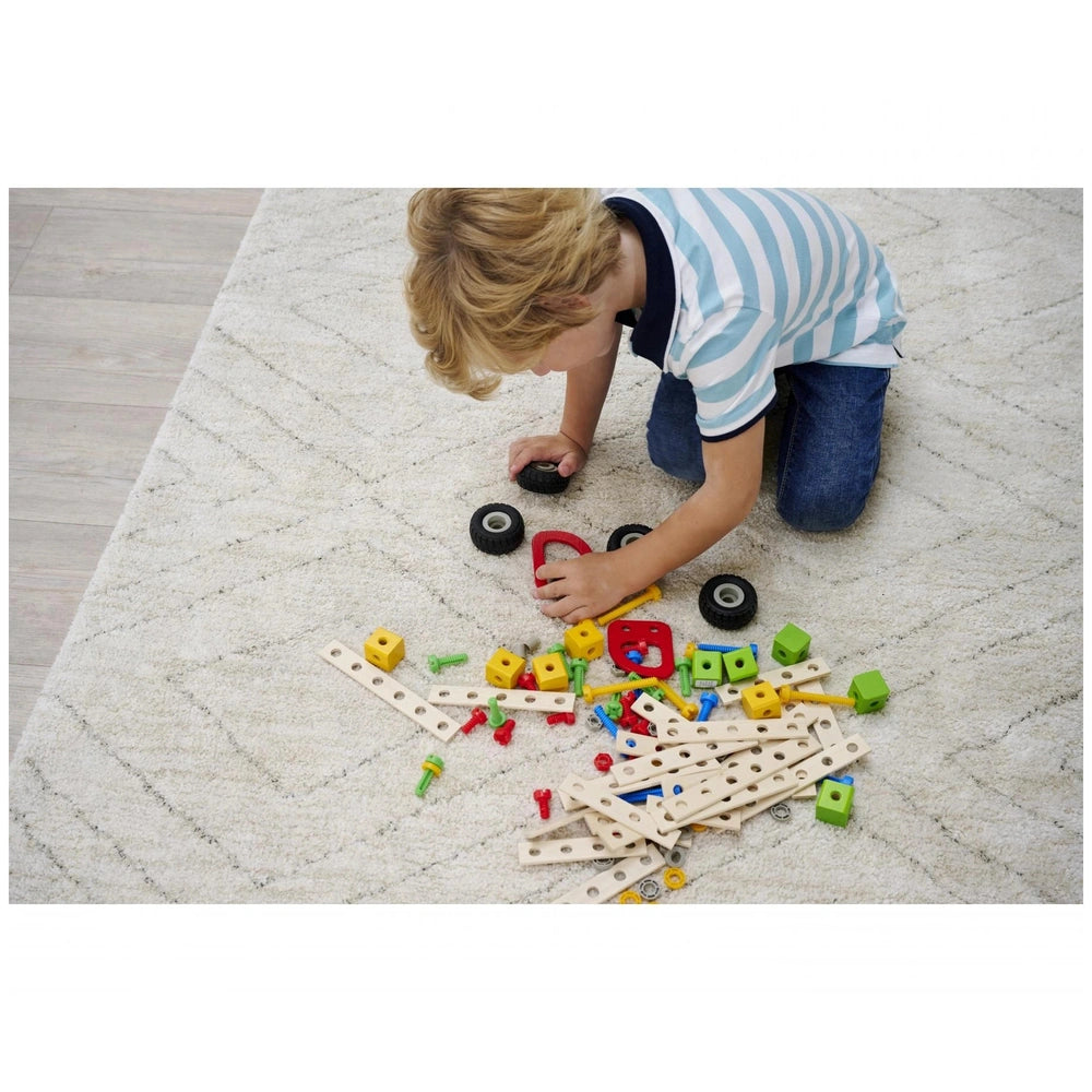Eichhorn construction set toys in yellow, red, and blue are scattered on a carpet as a child builds and plays.