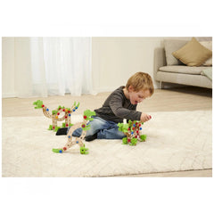 Eichhorn Constructor Dinosaur toy with green and blue wooden parts is being played with by a child on a white rug indoors.
