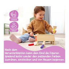 Eichhorn Knocking Game Pop Up: A child in a brown sweater and jeans plays with a wooden toy, smiling joyfully on a carpet.