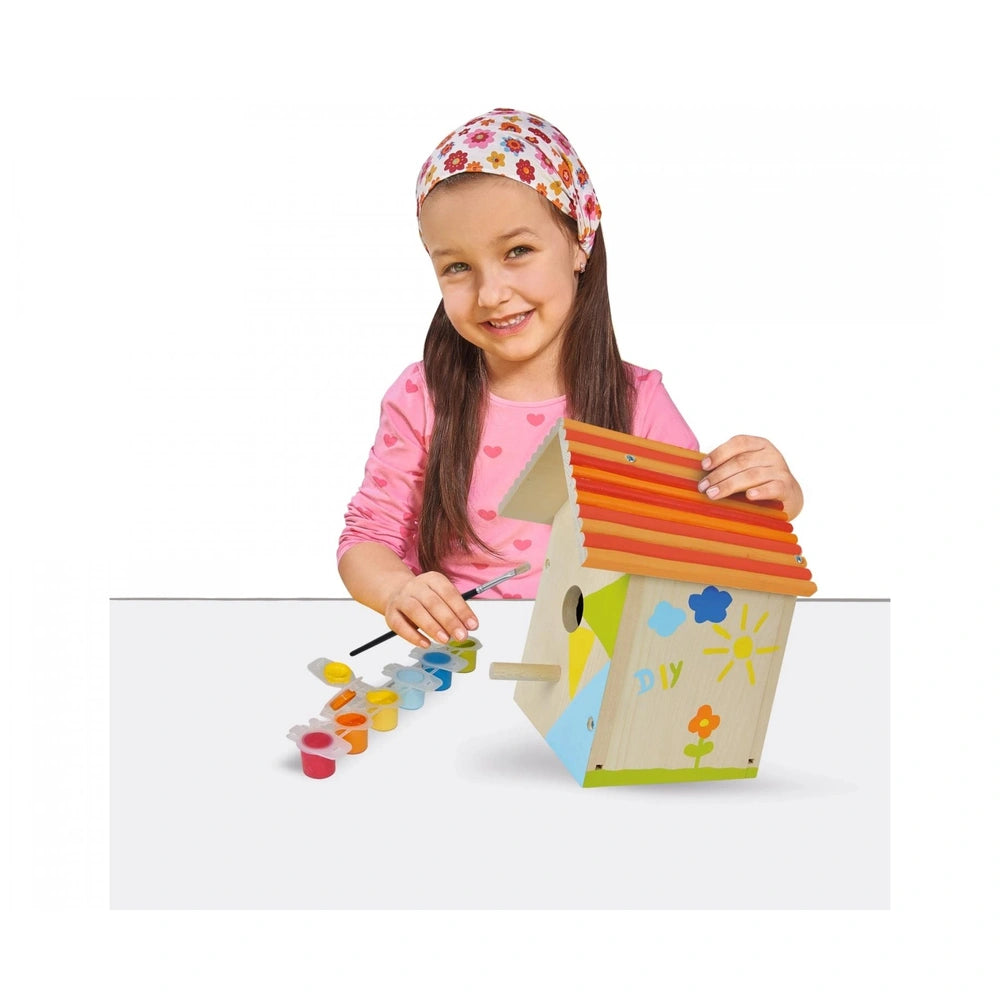 Eichhorn outdoor make your own birdhouse kit with a young girl painting a colorful toy house in a bright, clear setting.