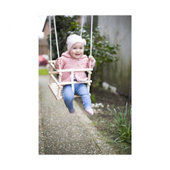 Eichhorn Outdoor Wooden Baby Swing with a smiling child in a pink jacket enjoying playtime in a garden setting.