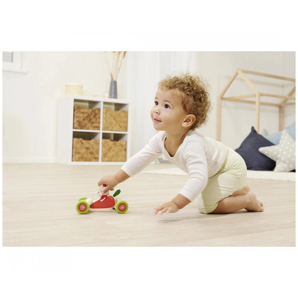 Eichhorn Push Vehicle with a smiling child holding a toy car on a wooden floor in a bright, modern play area.