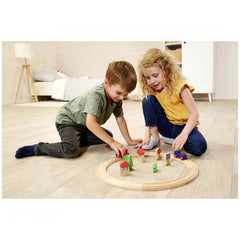 Eichhorn train track playset with two children playing on a wooden floor, surrounded by various colorful train pieces.