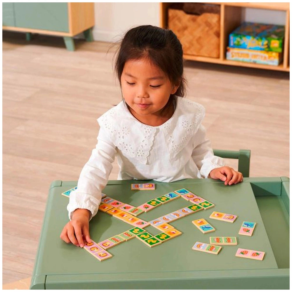 Eichhorn Wooden Domino Game with a young girl arranging colorful blocks on a green table in a cozy, well-lit room.