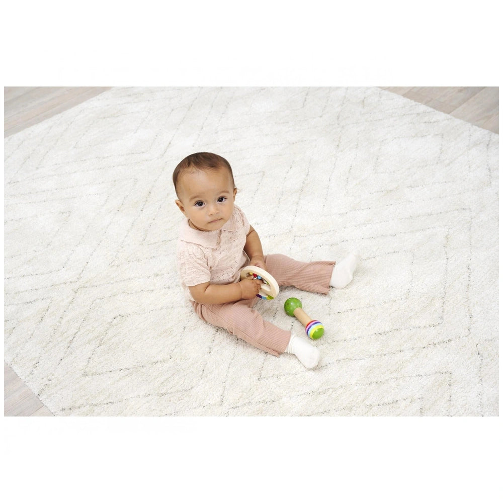 Eichhorn Wooden Music Set featuring a child joyfully holding a colorful rattle on a patterned floor in soft indoor lighting.