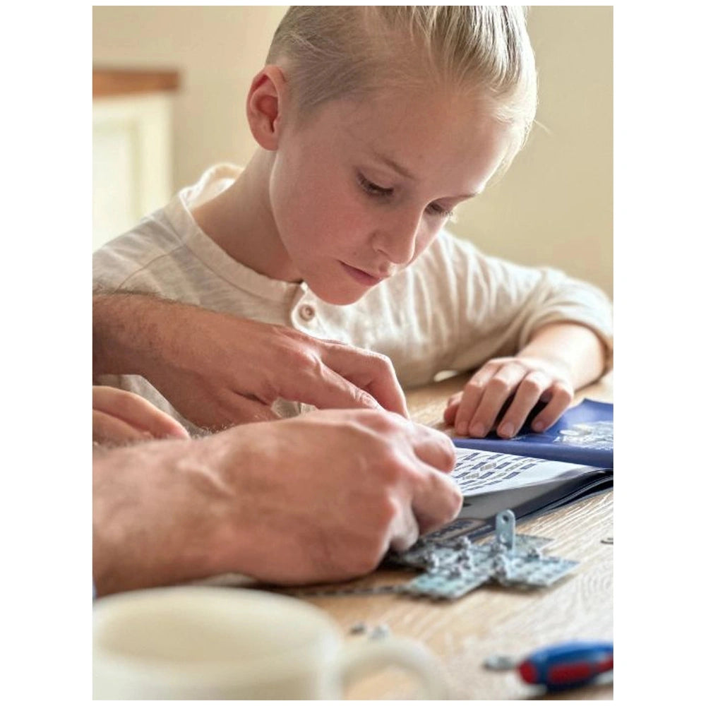 Eitech Racing Car construction set being assembled by a child on a wooden tabletop with a plastic keyboard nearby.