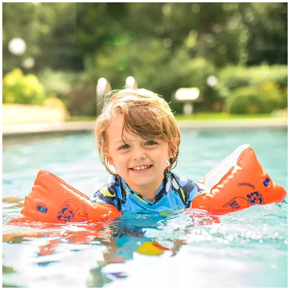 Happy People Bema Arm Rings on a smiling child wearing a blue swimsuit and orange swim fins in a swimming pool.