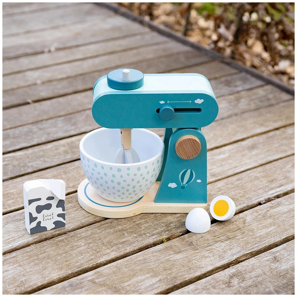 Label-Label food processor toy features a polka dot bowl, cow print carton, plastic egg, and spoon on a wooden surface.