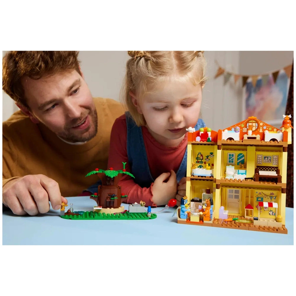 A father and daughter play together with the LEGO Bluey’s Family House set, featuring colorful rooms and playful minifigures.