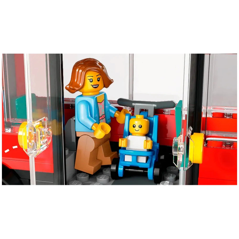 A LEGO City scene featuring a smiling woman in a blue jacket pushing a blue stroller with a baby inside, set against a bright red double-decker bus backdrop.