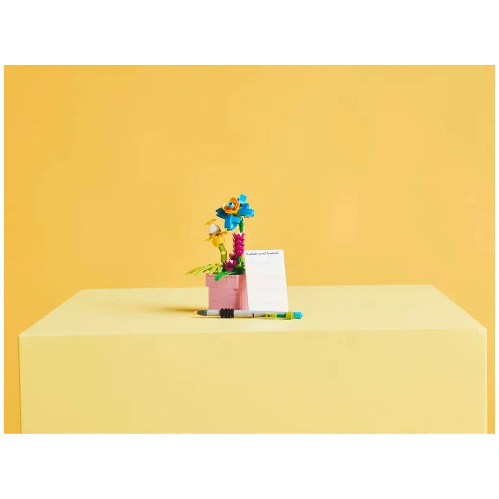 Colorful LEGO Creator Typewriter construction set featuring a mini typewriter, vibrant flowers, and a notepad on a pastel yellow background.