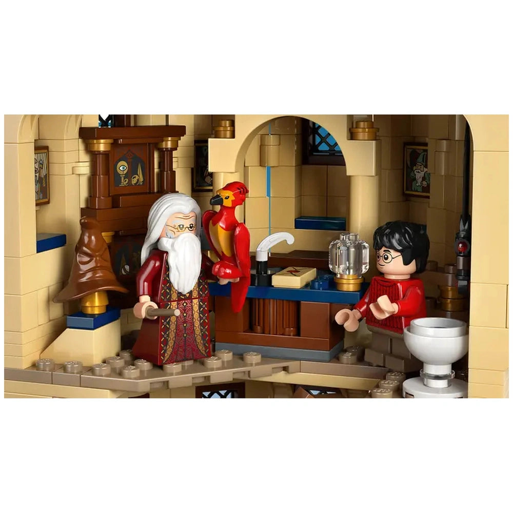Dumbledore with a long white beard holds a red and yellow phoenix next to Harry Potter in a detailed Hogwarts office setting, featuring a blue desk, a cauldron, and various magical elements.