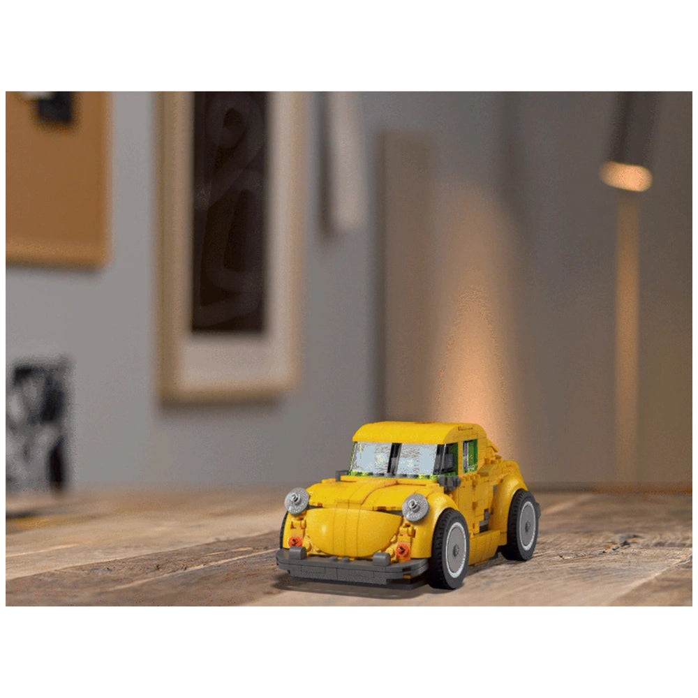LEGO® Icons Bumblebee construction set in bright yellow, showcasing a detailed robot car on a wooden table.