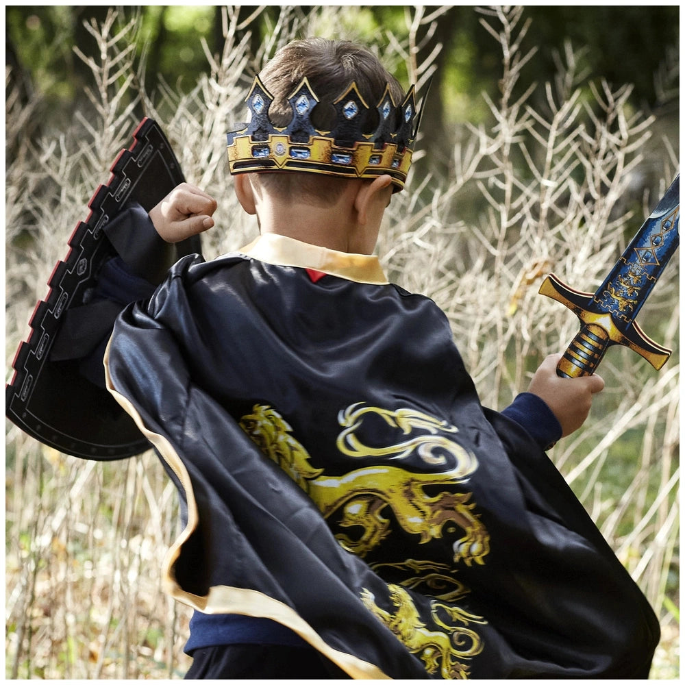 Child in a shiny blue and gold crown, dark dragon-patterned cape, holding a metallic sword, embodying a king character.